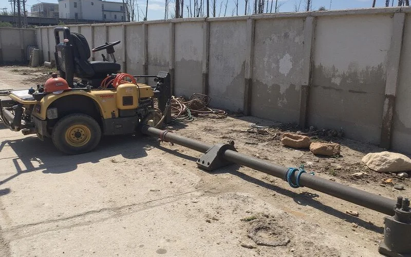 Helical tieback anchor staged near a shoreline retaining structure