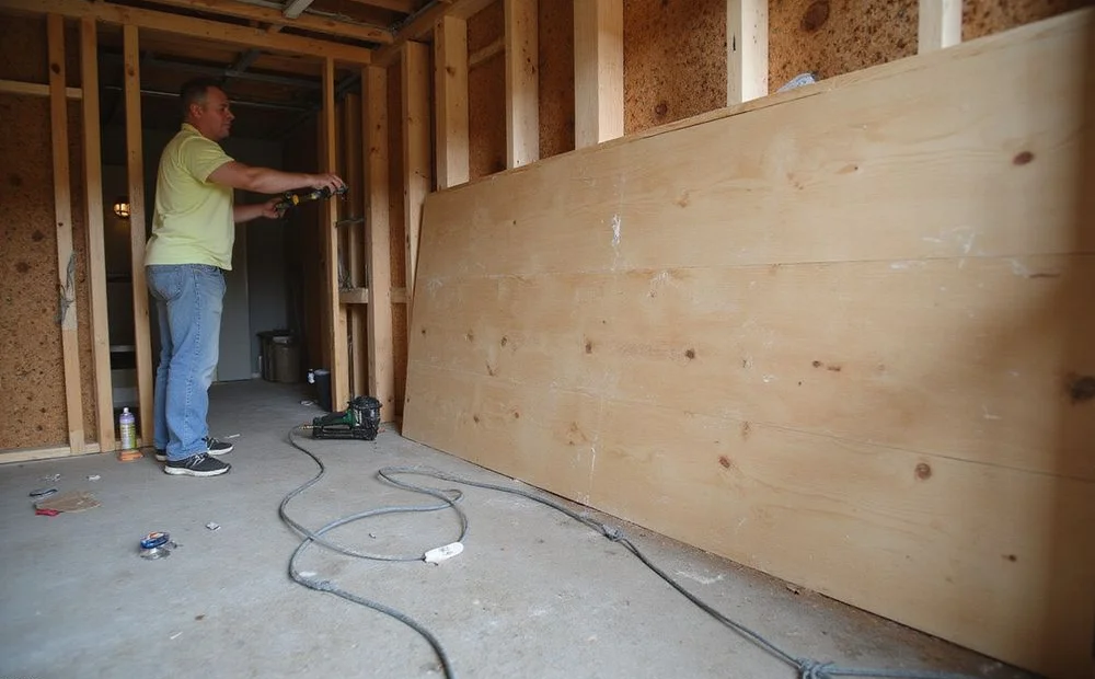Structural plywood shear panel being fastened to cripple wall studs in an older Seattle basement